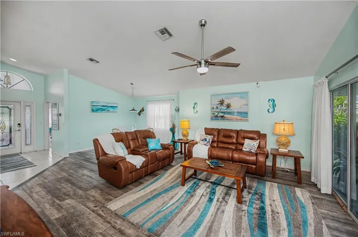 Spacious living area featuring wood-finish flooring, a ceiling fan, and sliding glass doors