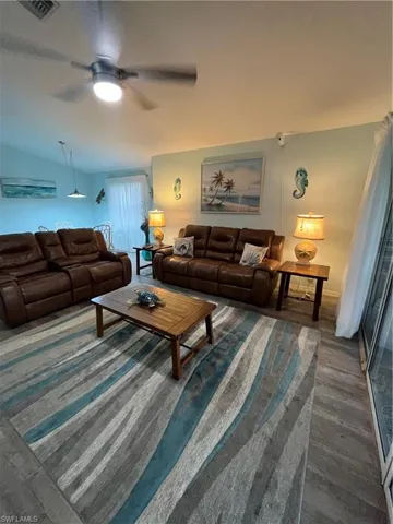 Expansive living area featuring wood-finish flooring, a ceiling fan with integrated lighting, and recessed lighting