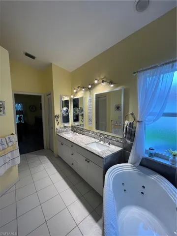 Spacious bathroom featuring a dual vanity with granite-look countertops, undermount sinks, and a tile backsplash