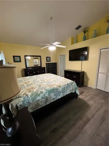 Spacious bedroom featuring wood-finish flooring, vaulted ceilings, and a ceiling fan with integrated lighting