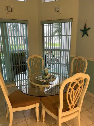Dining area featuring a circular glass-top table and four chairs with carved backrests