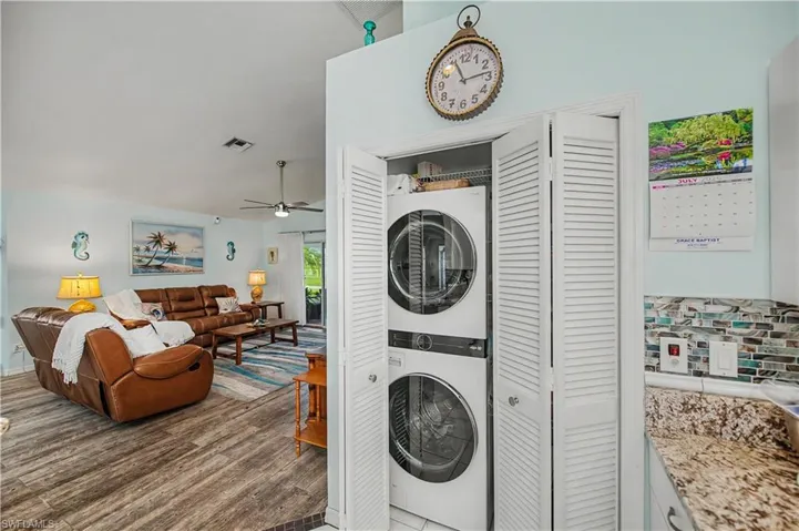 Laundry closet with stacked appliances and louvered bifold doors