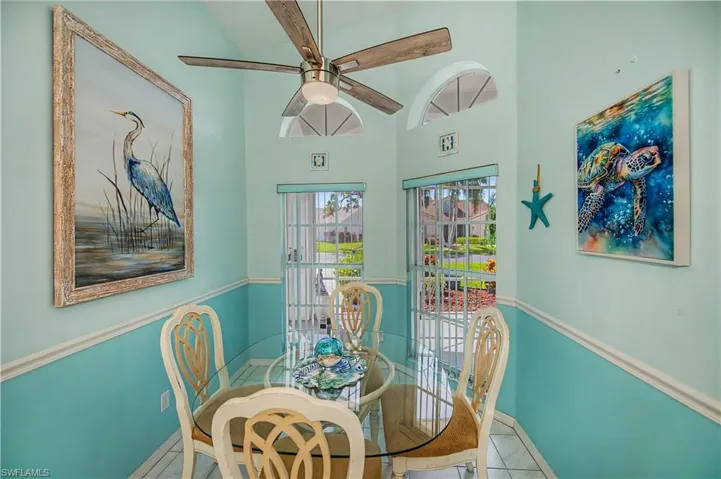 Vaulted ceiling with an integrated ceiling fan, two-tone wall treatment, and white tile flooring