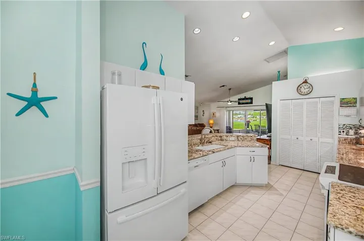 Kitchen featuring white appliances, granite countertops, white cabinetry, and recessed lighting