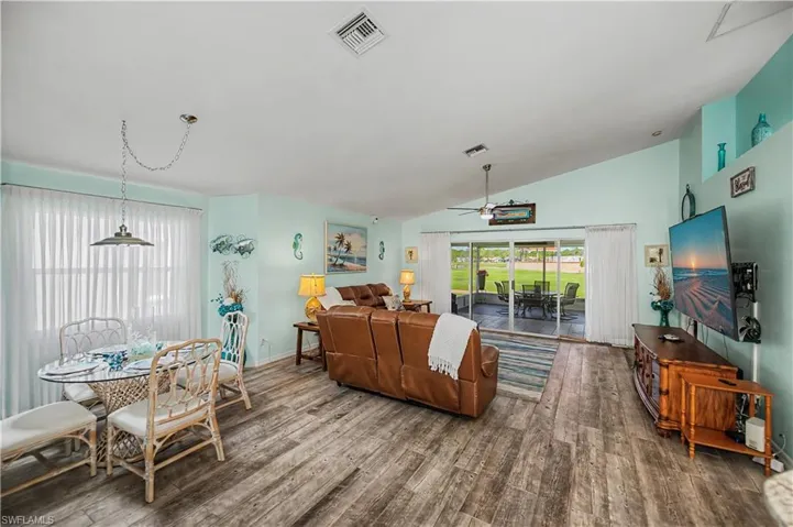 Living area featuring wood-finish flooring, vaulted ceiling, and light blue wall tones