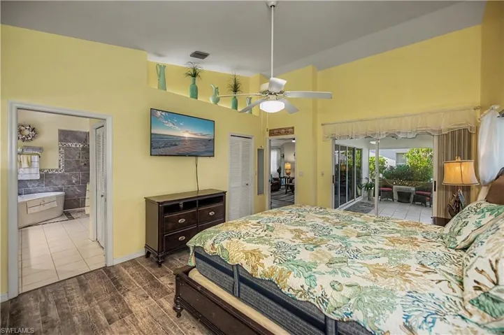 Spacious bedroom featuring wood-finish flooring, a ceiling fan, and direct access to an outdoor patio with tiled flooring