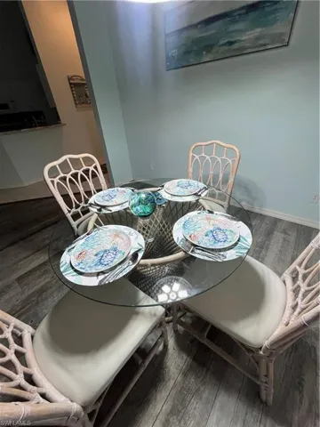 Dining area with wood-finish flooring, light blue wall paint, and a glass-top table