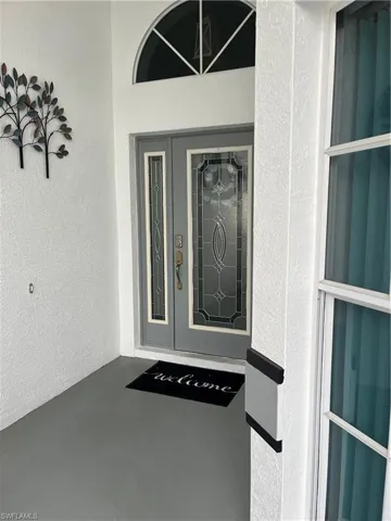 Entryway featuring double doors with decorative glass panels and an arched transom window