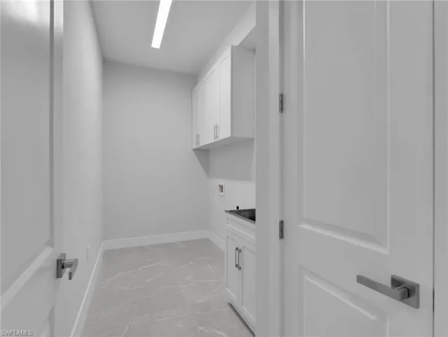 Washroom featuring hookup for an electric dryer, washer hookup, baseboards, marble finish floor, and cabinet space