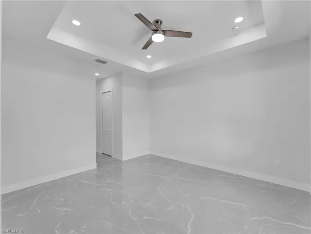 Unfurnished room with a tray ceiling, baseboards, and recessed lighting
