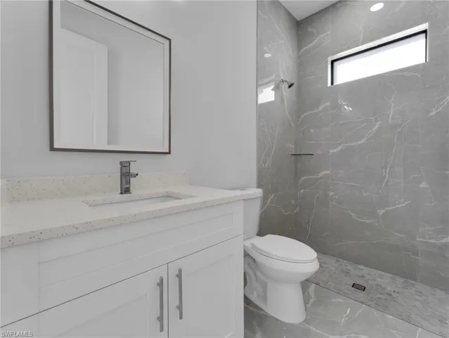 Full bath with toilet, marble finish floor, a marble finish shower, and vanity