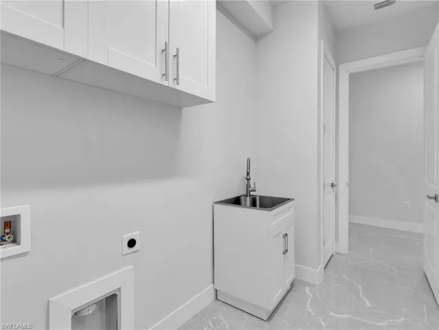 Laundry room with cabinet space, marble finish floor, hookup for a washing machine, hookup for an electric dryer, and a sink