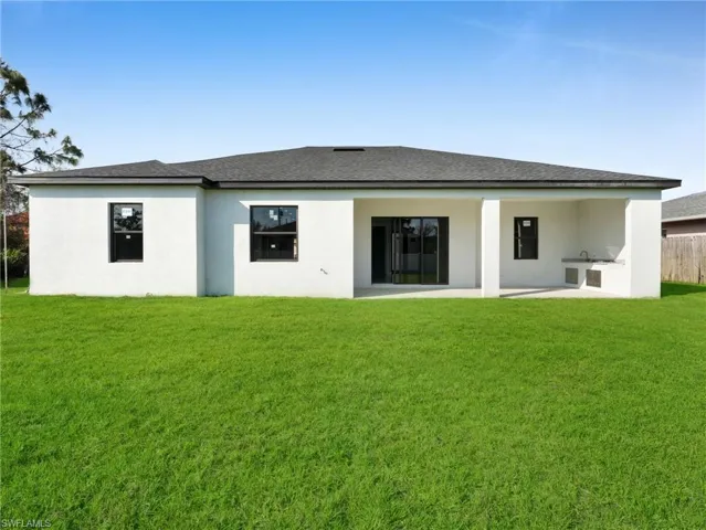 Rear view of property featuring a shingled roof, a lawn, area for grilling, a patio, and stucco siding