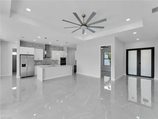 Kitchen with stainless steel appliances, white cabinets, open floor plan, light countertops, and a raised ceiling