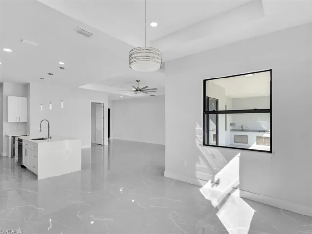 Spare room with a ceiling fan, visible vents, a raised ceiling, and a sink