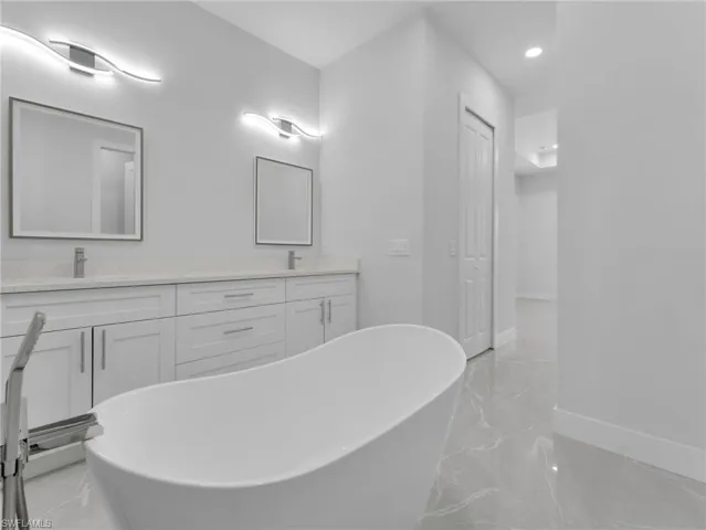 Bathroom featuring a sink, marble finish floor, a freestanding bath, and a closet