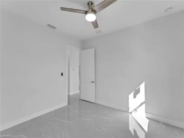Empty room with a ceiling fan, visible vents, and baseboards