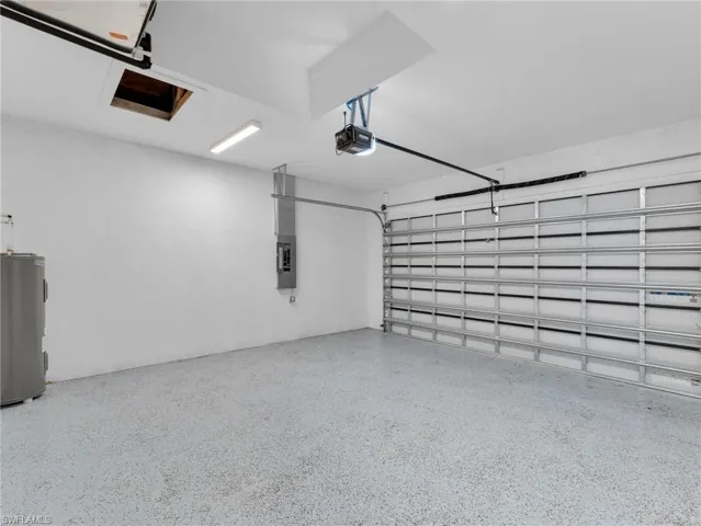Garage featuring a garage door opener, electric panel, and water heater