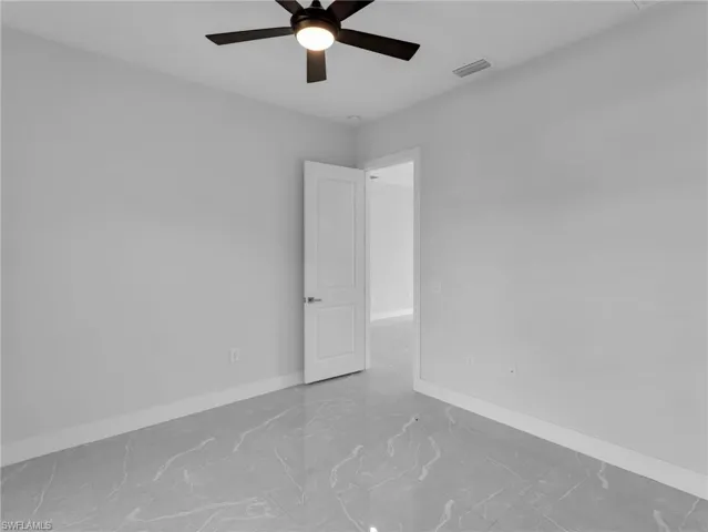 Unfurnished room with marble finish floor, a ceiling fan, visible vents, and baseboards