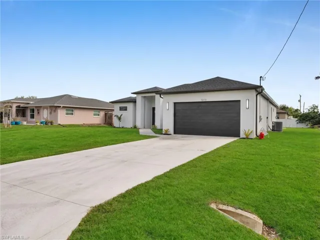 Prairie-style house with driveway, an attached garage, a front lawn, and stucco siding