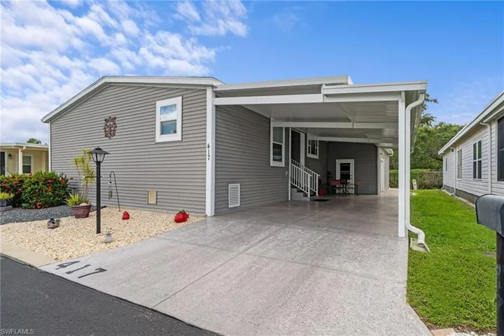 Covered carport with concrete surfacing, white railing, and exterior lighting