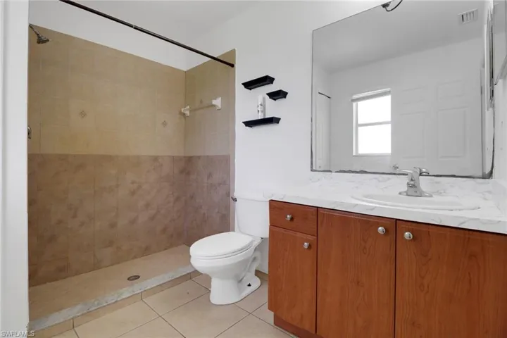 Bathroom with vanity, tiled shower, and tile patterned floors