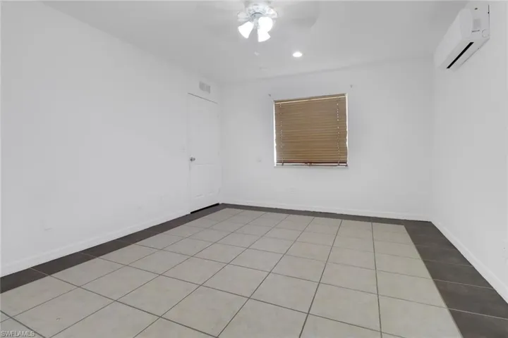 Empty room with a wall mounted air conditioner, tile patterned floors, ceiling fan, and recessed lighting