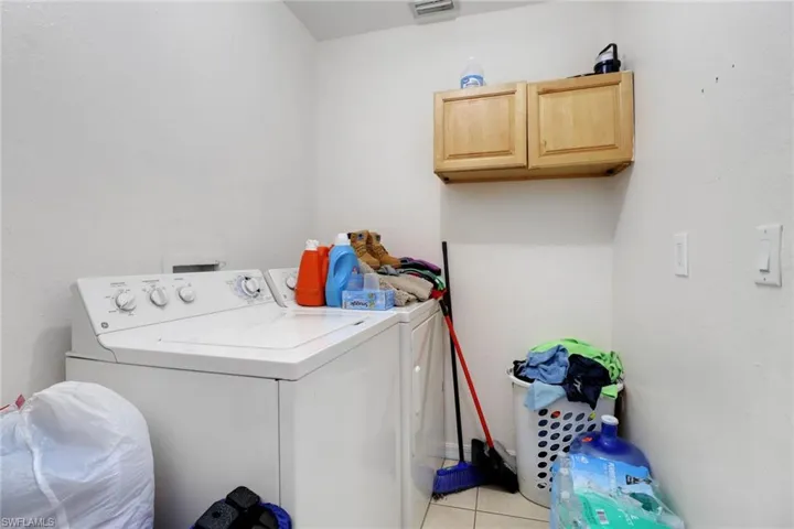 Washroom with washer and dryer, cabinet space, and light tile patterned flooring