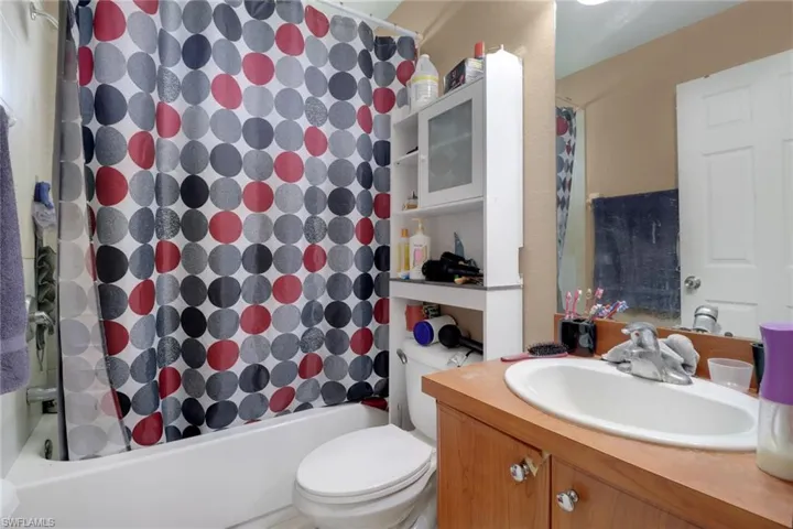 Bathroom featuring vanity and shower / bathtub combination with curtain