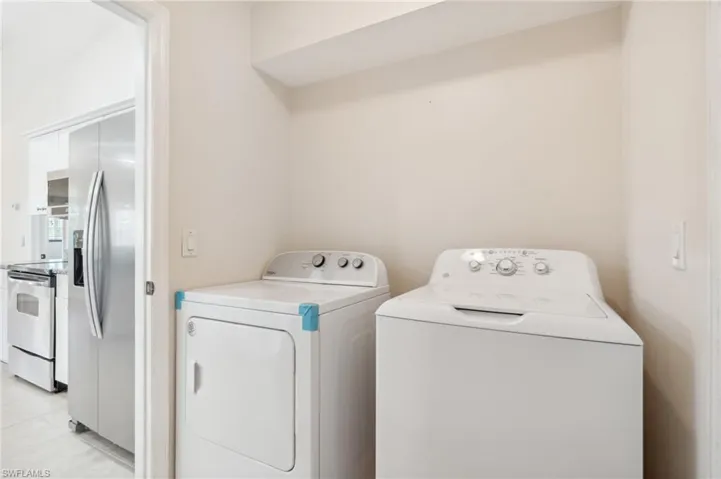 Laundry room featuring washer and clothes dryer and light tile patterned flooring