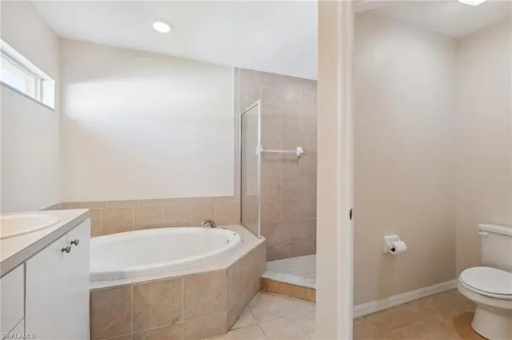 Full bathroom featuring vanity, toilet, tile patterned floors, and shower with separate bathtub