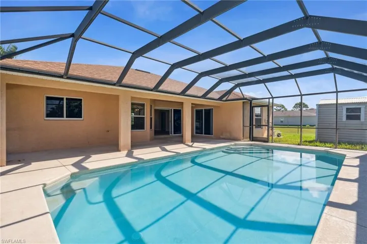 View of pool with glass enclosure and a patio area