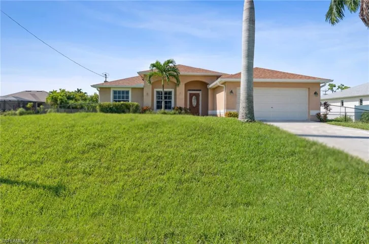 View of front of property featuring a garage and a front lawn