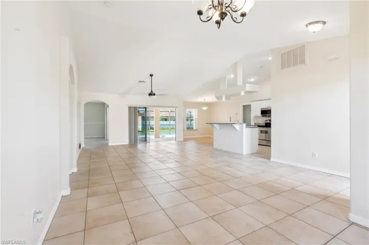 Unfurnished living room with an inviting chandelier, high vaulted ceiling, and light tile patterned flooring