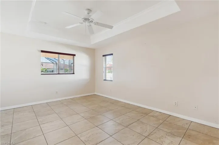 Spare room featuring a raised ceiling, ceiling fan, and ornamental molding