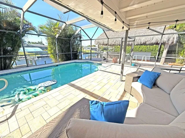 Swimming pool featuring a lanai, a water view, a sunroom, and a patio