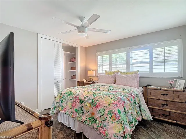 Bedroom with dark wood-style floors, a closet, and a ceiling fan