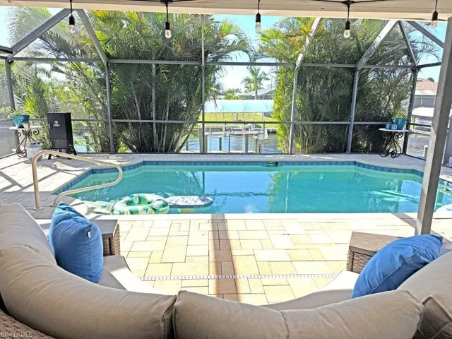 Swimming pool featuring glass enclosure, a sunroom, and a patio area