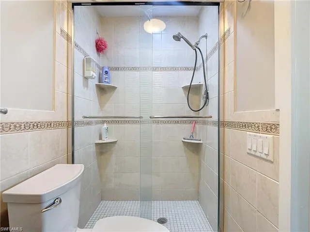 Bathroom featuring tile walls and a shower stall