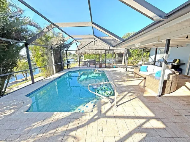 Swimming pool featuring a sunroom, a lanai, a patio area, outdoor lounge area, and area for grilling