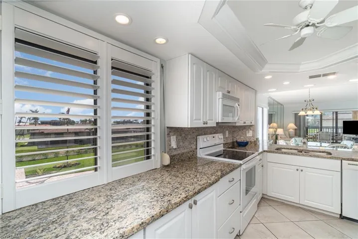 Kitchen featuring white appliances, a sink, a raised ceiling, recessed lighting, and decorative backsplash