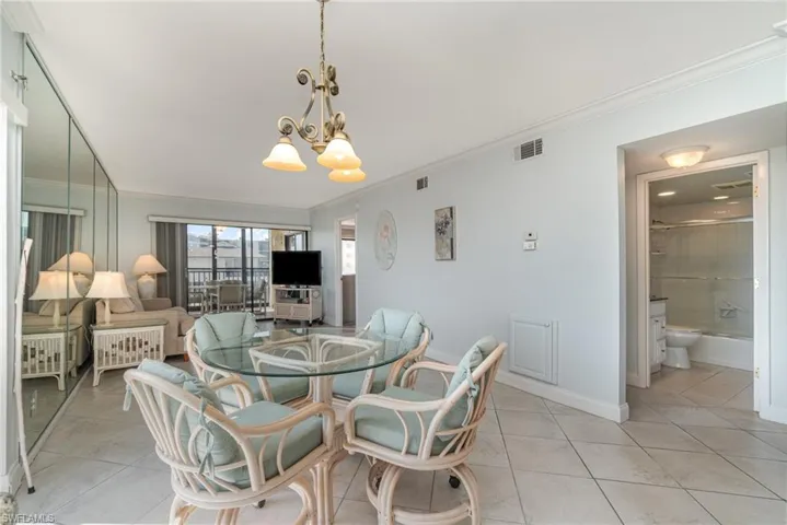 Dining area featuring ornamental molding, a chandelier, light tile patterned flooring, and baseboards
