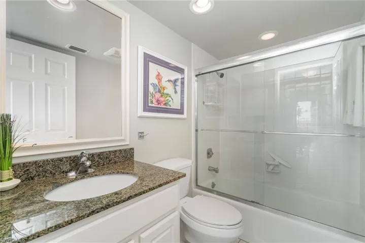 2nd Bathroom with granite countertop, tiled shower and glass shower doors.