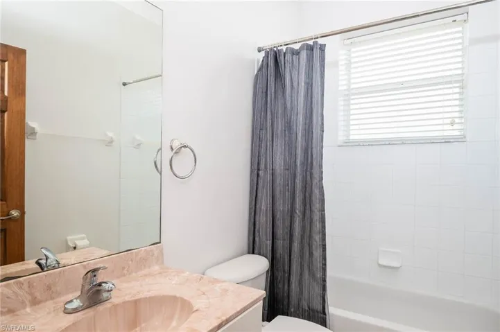 Bathroom featuring toilet, vanity, and shower / bath combination with curtain
