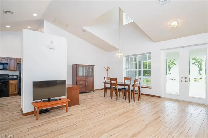 Dining area featuring a chandelier, high vaulted ceiling, wood baseboards, and french doors