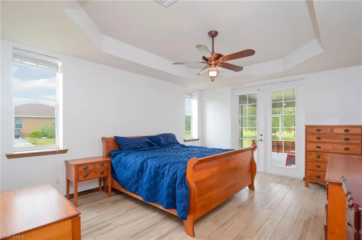 Bedroom with a tray ceiling, access to exterior, multiple windows and French doors