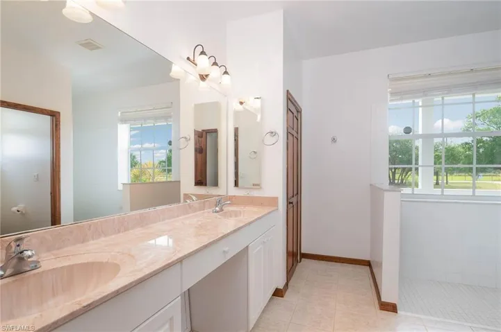 Full bathroom with tile patterned flooring, double vanity, and baseboards