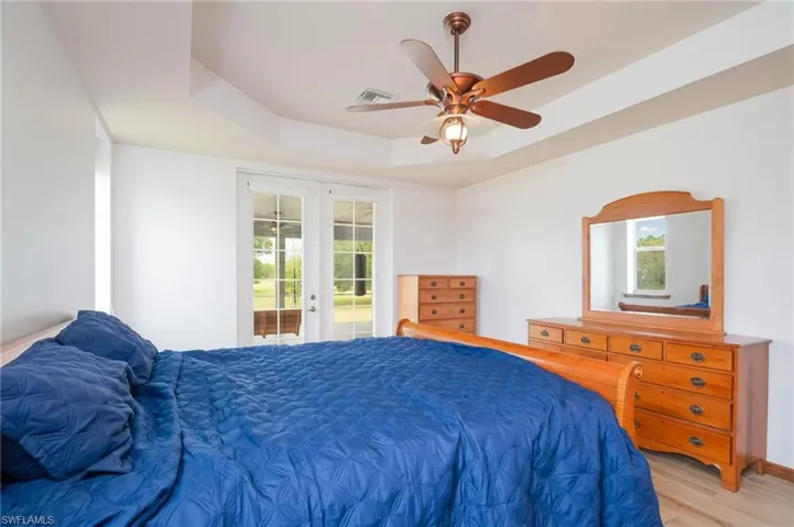 Bedroom with french doors, access to exterior, a tray ceiling, , and ceiling fan