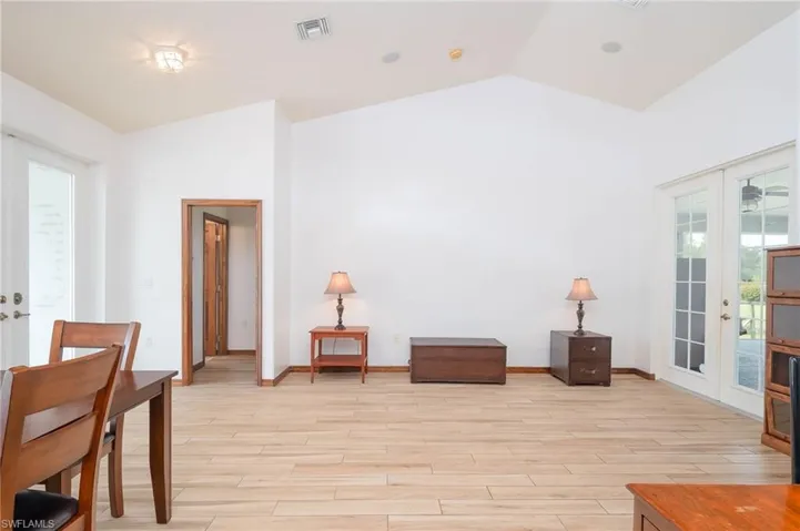 Living area with french doors, wood baseboards, and vaulted ceiling
