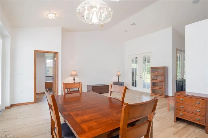 Living Room and Dining room featuring french doors, a chandelier, lofted ceiling, and wood baseboards